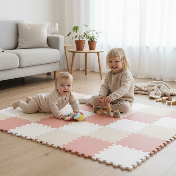 Zwei Kinder spielen auf einer quadratischen Puzzlematte aus Schaumstoff in einem hellen Wohnzimmer mit Holzboden.