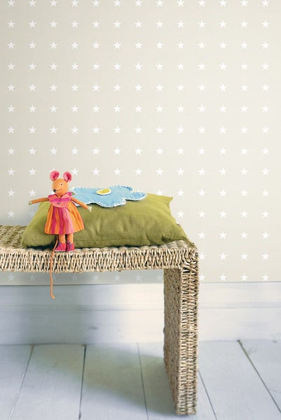 Szene mit einer Sternen-Tapete, einem Rattantisch, einem grünen Kissen und einem Spielzeug