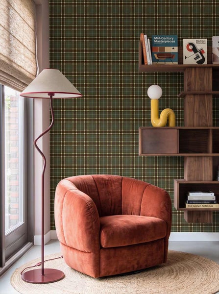 Modernes Wohnzimmer mit einer grün-braun karierten Tapete, einem weichen Sessel, einer Stehlampe und einem Wandregal aus Holz.