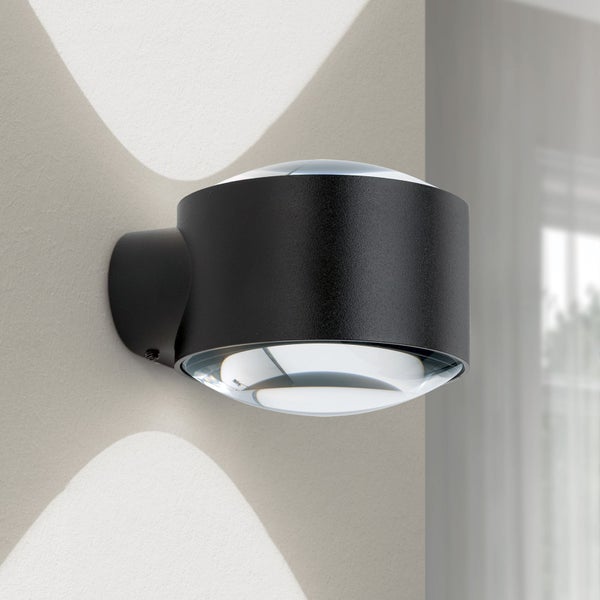 Zylinderförmige Wandleuchte in Schwarz mit Lichtaustritt nach oben und unten durch Glaslinsen.