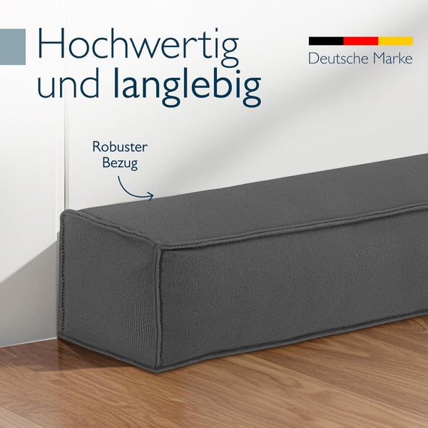 Grauer Zugluftstopper mit robustem Bezug auf Holzfußboden. Der Text hebt hochwertige Qualität, Langlebigkeit und eine deutsche Marke hervor.