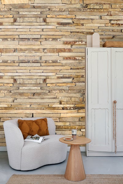 Wohnzimmer-Szene mit Sofa, Kissen, Tagesdecke, Beistelltisch und blauem Teppich