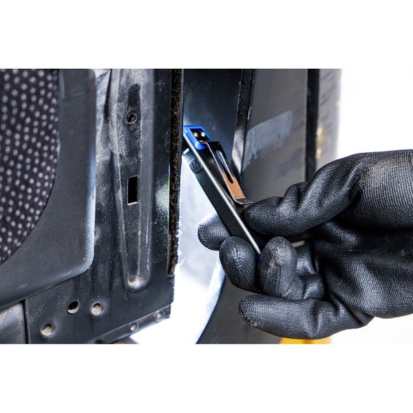 Eine Hand in einem Arbeitshandschuh hält eine schmale LED-Inspektionsleuchte und leuchtet in einen engen Spalt an einem Metallbauteil.