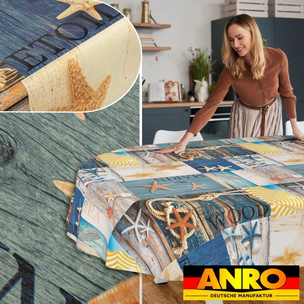 Eine Frau breitet eine abwischbare Tischdecke mit maritimem Muster aus Seesternen und Holzoptik in einer hellen Küche aus. ANRO Logo.