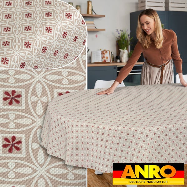 Eine Frau legt eine abwaschbare runde Tischdecke mit geometrischem Blumenmuster auf einen Küchentisch, ANRO Logo.