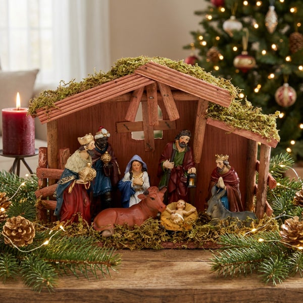 Detaillierte Weihnachtskrippe aus Holz mit Figuren der Heiligen Familie und Heiligen Drei Königen, dekoriert mit Moos auf dem Dach.