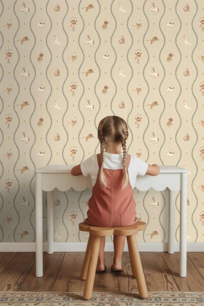 Hell gestaltetes Kinderzimmer mit einer Tapete mit Zirkustieren und Wellenlinien, einem weißen Schreibtisch und einem Hocker aus Holz in Blumenform.