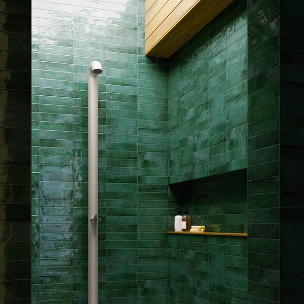 Moderne Dusche mit grünen Wandfliesen in Ziegeloptik, minimalistischer Duscharmatur und integrierter Wandnische als Ablage.