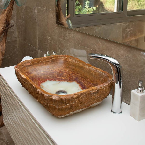 Modernes Badezimmer mit einem Aufsatzwaschbecken aus Naturstein in rustikaler Optik auf einem weißen Waschtisch mit verchromter Armatur.