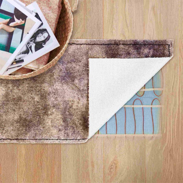 Bild einer Teppichheizung auf Holzboden, Ecke des Teppichs ist hochgeklappt