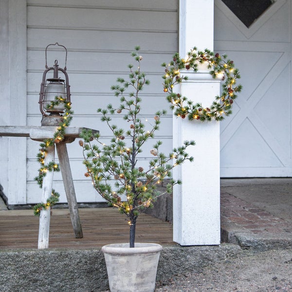 Dekorierte Veranda mit Tannenbaum im Topf, Türkranz und Laterne