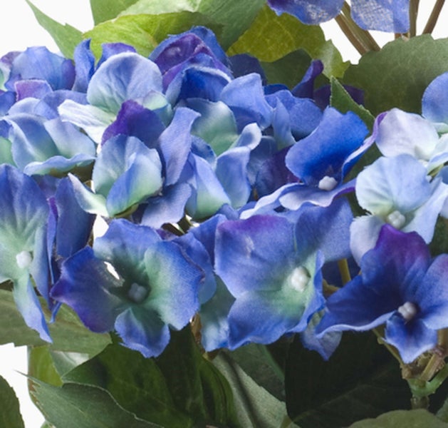 Künstliche Hortensie in Blau und Violett mit grünen Blättern.