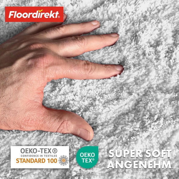 Nahaufnahme eines weißen, superweichen Teppichs mit Hand und den Logos Floor direkt und Öko-Tex.
