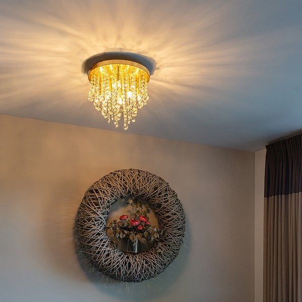 Deckenleuchte mit Kristallen und einem Kranz mit Blumen an der Wand.