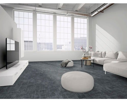 Moderner Wohnraum im Loft-Stil mit dunkelgrauen Teppichfliesen, großem Sofa, weißem Lowboard und hellen Fenstern.