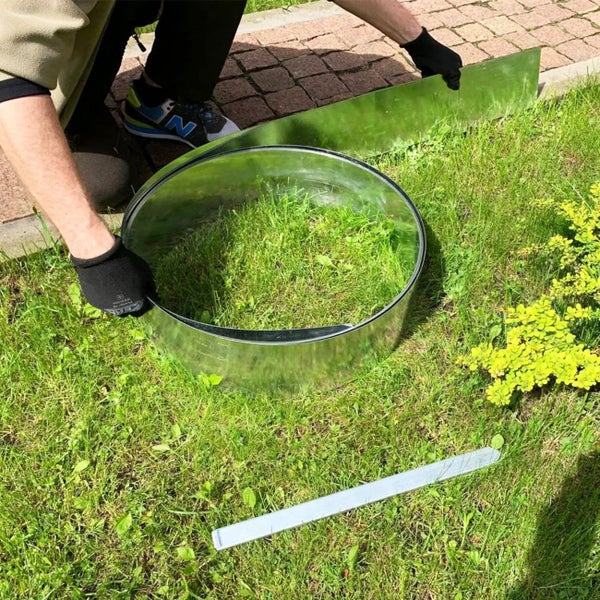 Person formt mit Rasenkantenband eine Beeteinfassung im Garten.