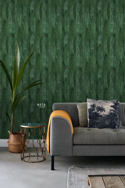 Dekorative grüne Tapete mit Blattformmuster hinter einem grauen Sofa