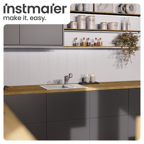 instmaler Logo in einer modernen Küche mit dunkelgrauen Schränken, hölzerner Arbeitsplatte, Fischgräten-Fliesen und Beleuchtung unter Regalen.