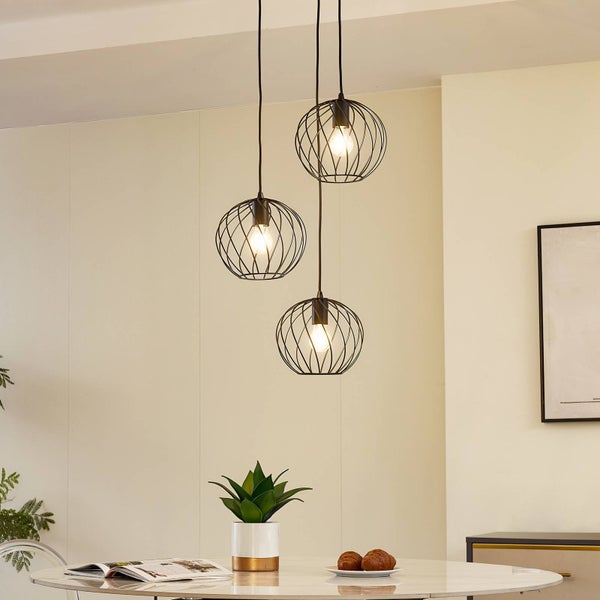 Hängelampe mit drei runden Lampenschirmen aus Metalldraht über einem Esstisch.