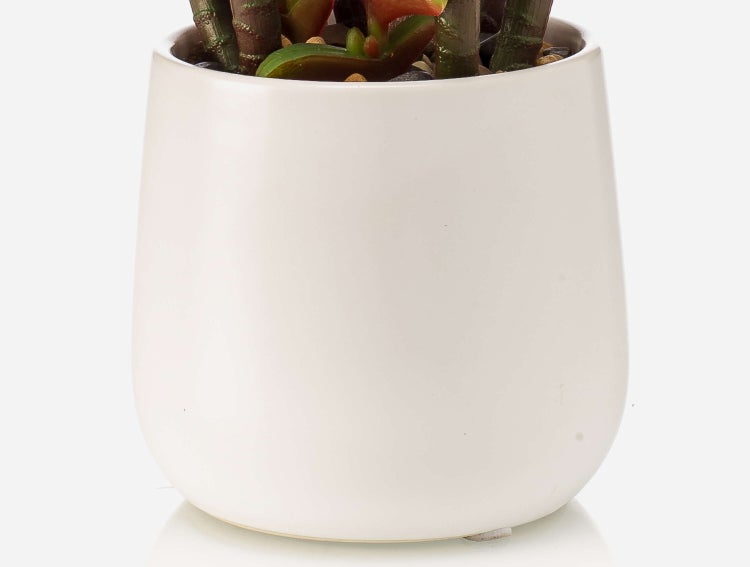 Künstliche Palme mit hohem Stamm und grünen Palmwedeln in einem schwarzen Topf aus Kunststoff.