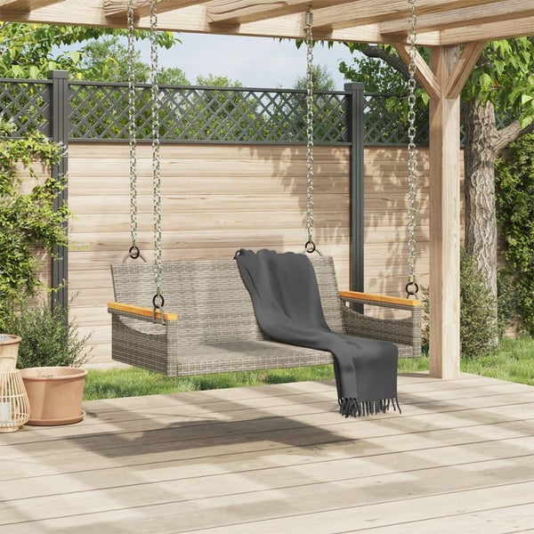 Gartenszene mit einer Schaukelbank aus Rattan, die an einer Holzpergola mit Ketten aufgehängt ist und eine Decke hat