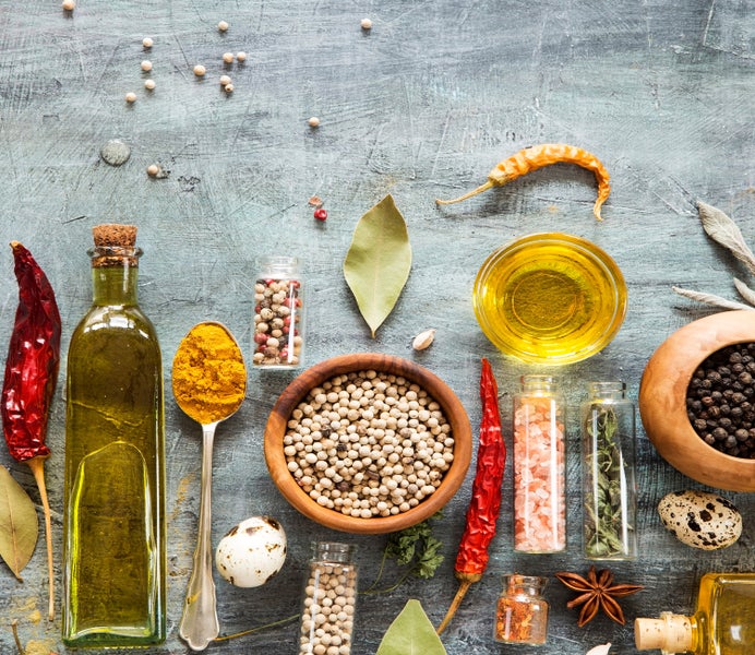 Zweiteilige Herdabdeckplatte aus Glas mit Gewürze-Motiv auf einem Kochfeld in einer modernen Küche mit dunklen Schränken.