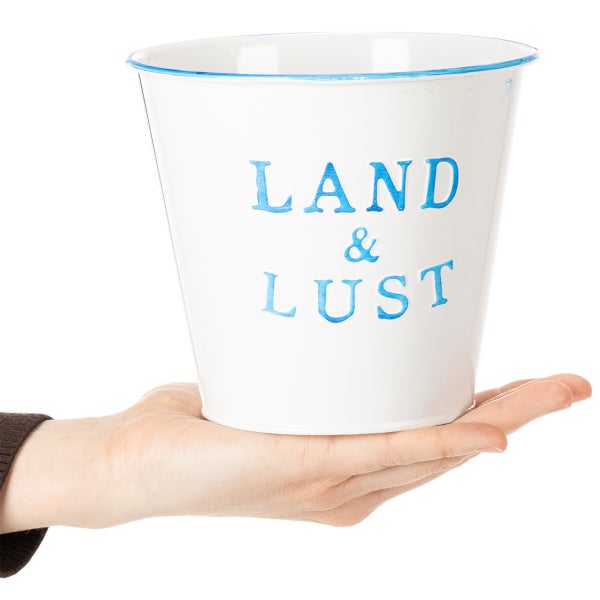 Kleiner weißer Blumentopf aus Metall mit blauem Rand und Schriftzug Land und Lust, in einer Hand gehalten zur Größendarstellung.