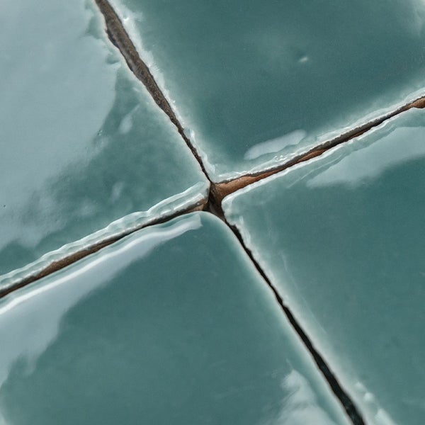 Nahaufnahme von quadratischen Wandfliesen mit glänzender Oberfläche und unebenen Kanten als Fliesenbelag.