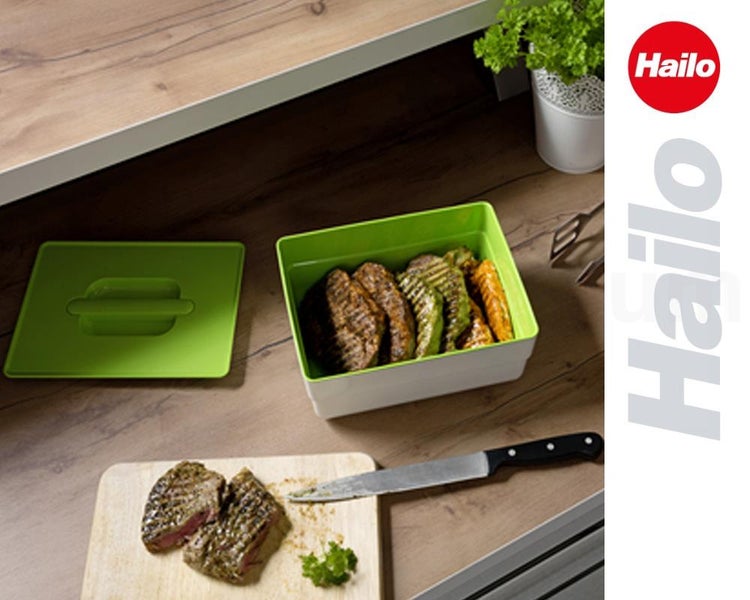 Hailo Aufbewahrungsbox mit Deckel auf Holzarbeitsplatte neben Fleisch auf einem Schneidebrett und einem Messer. Hailo Logo.