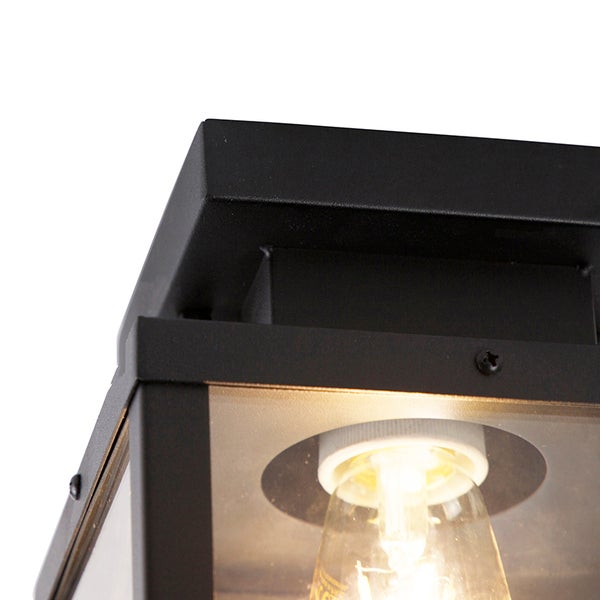 Nahaufnahme einer schwarzen Außenleuchte aus Metall und Glas mit eingeschaltetem Leuchtmittel.