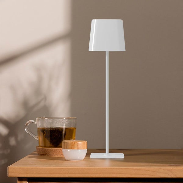 Weiße Tischleuchte neben Teetasse auf einem Holztisch