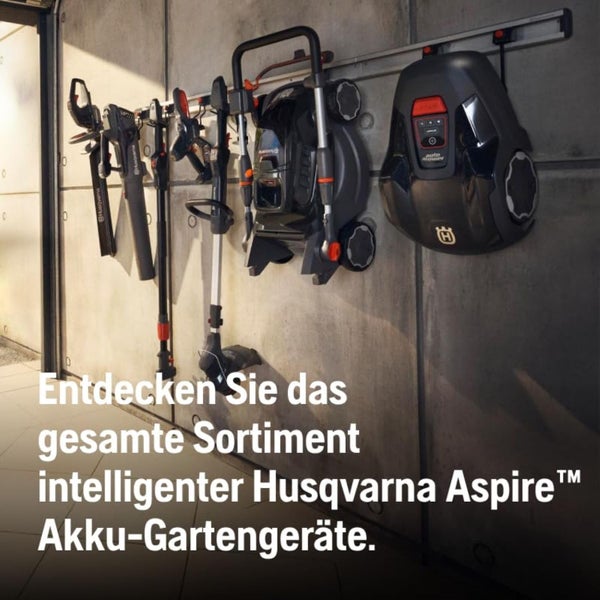 Husqvarna Aspire Akku-Gartengeräte Sortiment an einer Wand aufgehängt