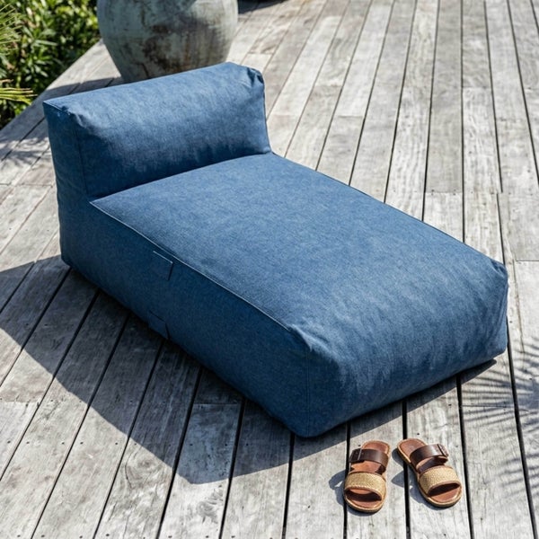 Blaue Outdoor-Sitzsackliege auf einer Holzterrasse mit einem großen Pflanzkübel und Sandalen.