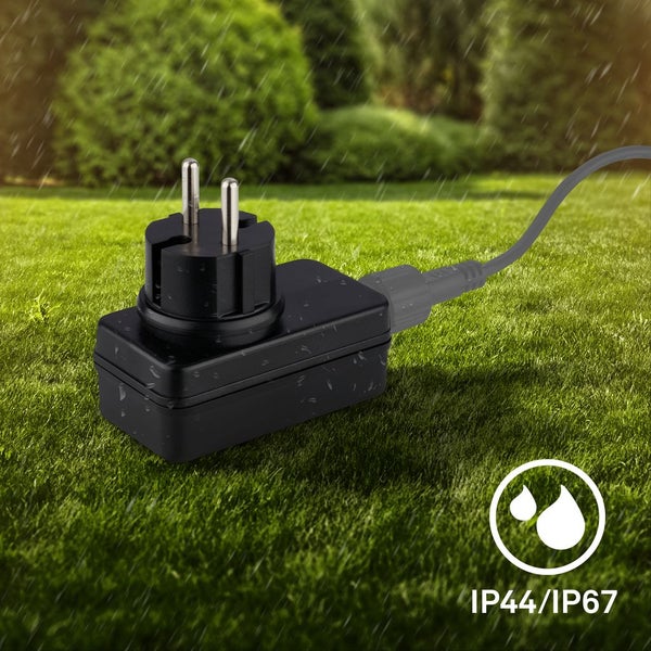 Wasserdichter Schutzkontaktstecker mit Netzteil auf einer Rasenfläche im Regen, Schutzart IP44 und IP67.