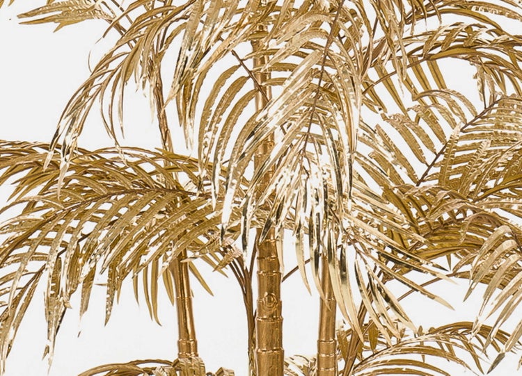 Künstliche goldfarbene Palme in einem schwarzen Topf.