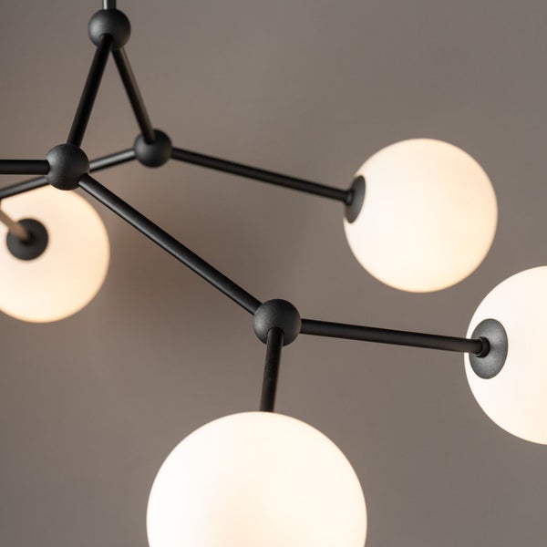 Moderne Pendelleuchte mit mehreren kugelförmigen Lampenschirmen und schwarzem Metallgestell.