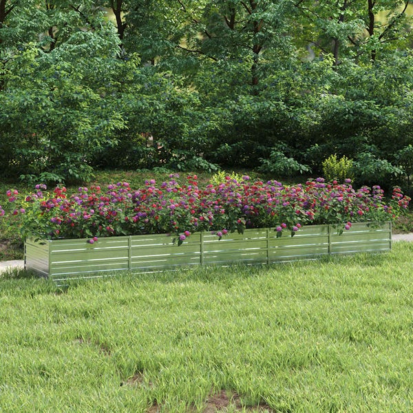 Rechteckiges Hochbeet aus verzinktem Metall mit bunten Blumen auf einer Rasenfläche vor Bäumen.
