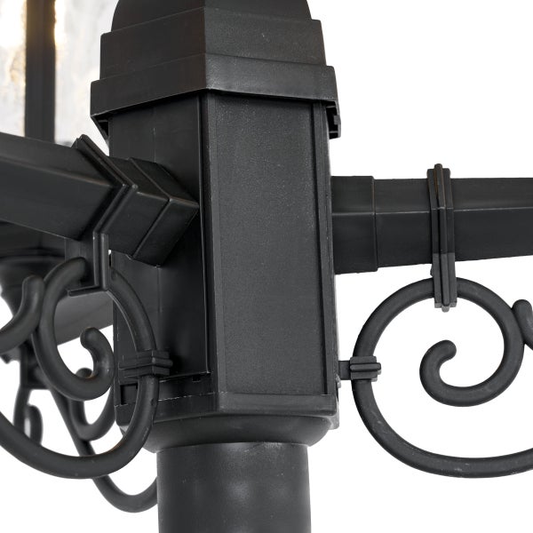 Nahaufnahme des Verbindungselements einer schwarzen Gartenlaterne aus Metall mit dekorativen Schnörkeln.