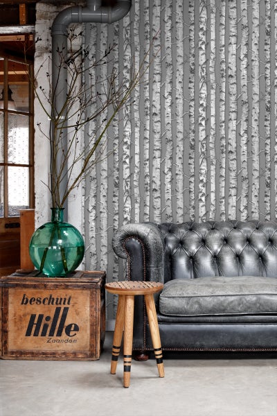 Wohnzimmer mit grauer Tapete mit Birkenmuster, Ledersofa und Holzhocker