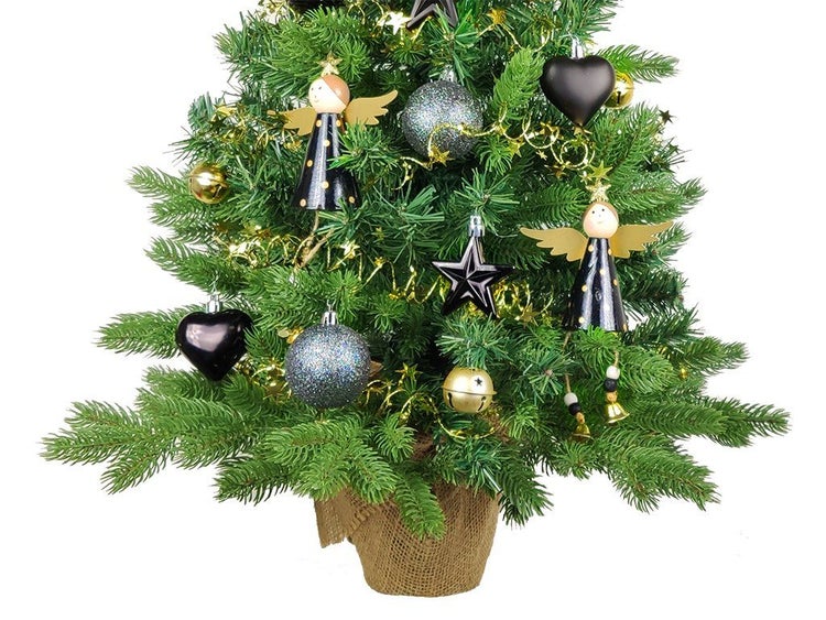 Ein geschmückter kleiner Weihnachtsbaum in einem Jutesack mit Engelanhängern, glitzernden Kugeln, Sternen und Lametta.