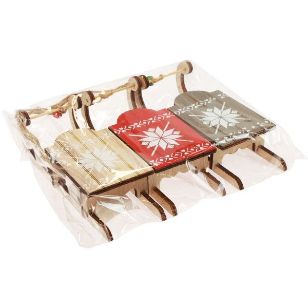 Dekorative Holzschlitten mit Schneeflockenmuster im Dreierset in einer transparenten Verpackung.
