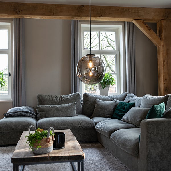 Wohnzimmer mit grauer Eckcouch, Holztisch und runder Pendelleuchte