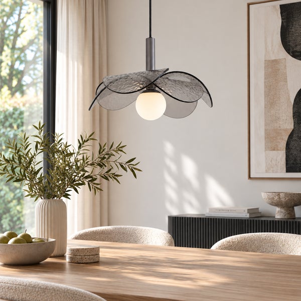 Moderne Pendelleuchte mit blütenförmigem Glasschirm über einem Holzesstisch in einem hellen, wohnlich eingerichteten Esszimmer.