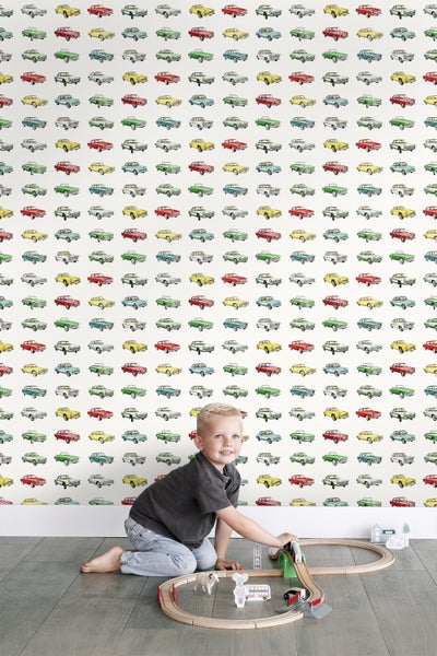 Tapete mit bunten Automotiven im Kinderzimmer, mit spielendem Kind auf dem Boden.