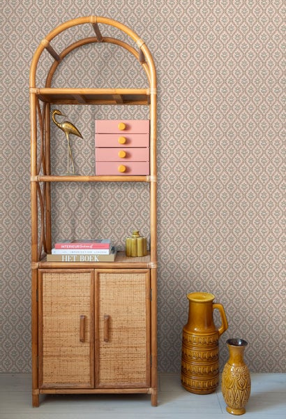 Vliestapete mit floralem Ornamentmuster hinter einem Rattanregal mit Dekorationsartikeln und Keramikvasen.
