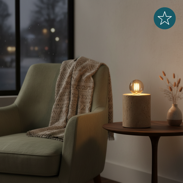 Dekorative Tischlampe auf einem Beistelltisch neben einem Sessel mit einer Decke