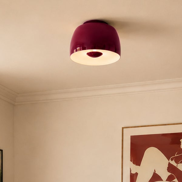 Moderne, kuppelförmige Deckenleuchte in Beere mit warmem Licht, montiert an einer hellen Zimmerdecke.