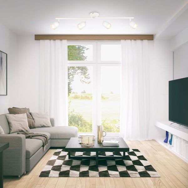 Vierflammiger Deckenstrahler in einem hellen Wohnzimmer mit grauem Ecksofa, schwarzem Couchtisch und Teppich mit Schachbrettmuster.