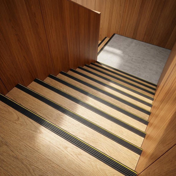 Holztreppe mit rutschfesten Trittkantenprofilen in modernem Interieur mit Holzverkleidung und Betonpodest.