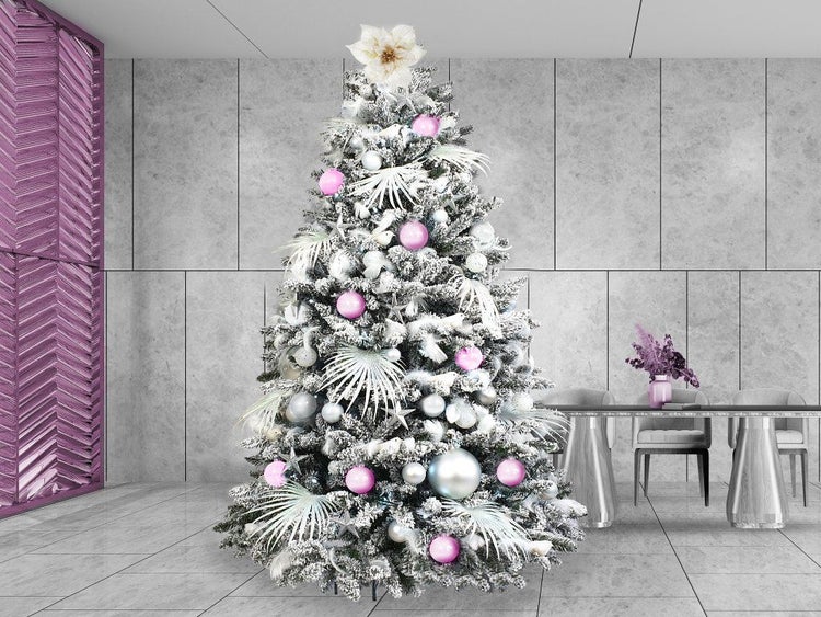 Künstlicher, beschneiter Weihnachtsbaum geschmückt mit Kugeln und floralen Elementen in modernem Interieur.
